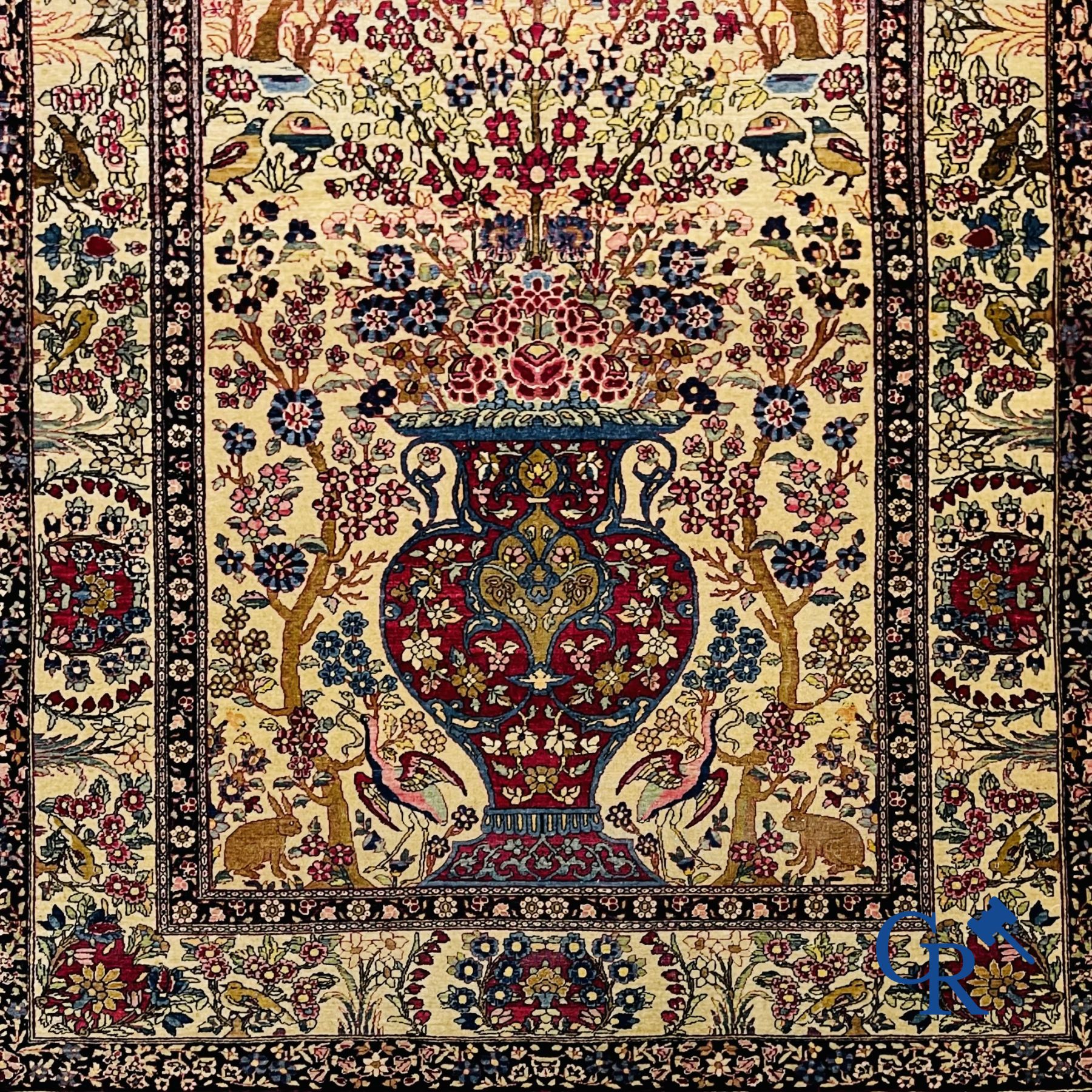 Tapis: Iran. Tapis persan avec un vase à fleurs, oiseaux et lapins dans un décor floral.